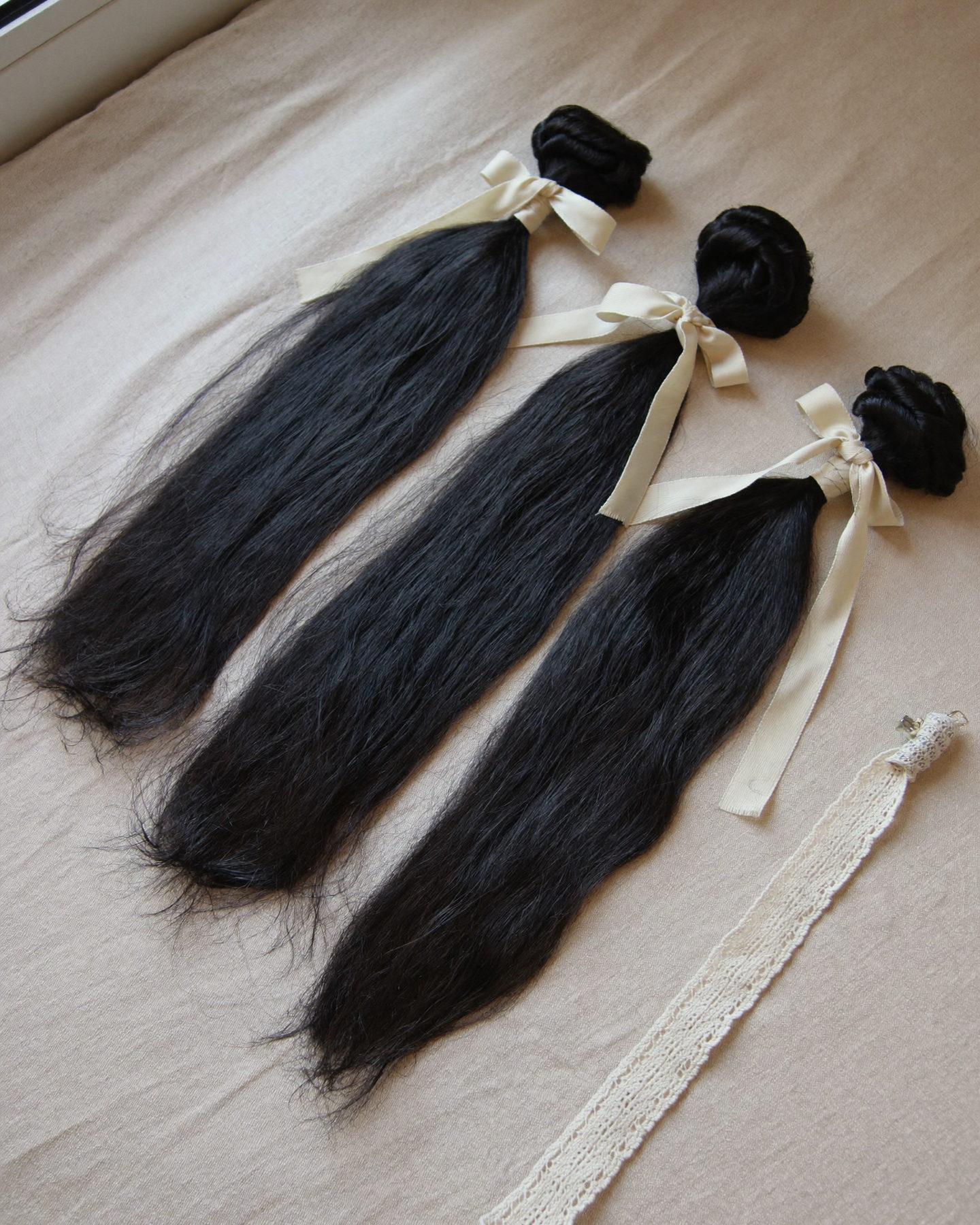 Three straight bundles tied with ribbon beside a lace closure